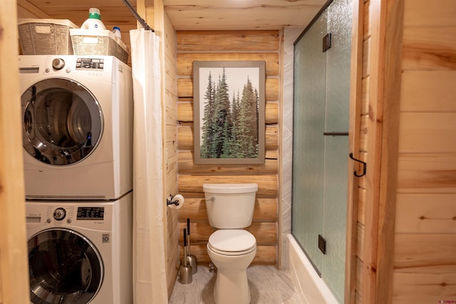 bathroom with shower / bath combination with glass door, toilet, and stacked washing maching and dryer