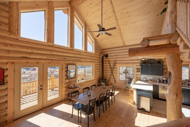 dining room with wood ceiling, a wood stove, french doors, light wood-style floors, and high vaulted ceiling