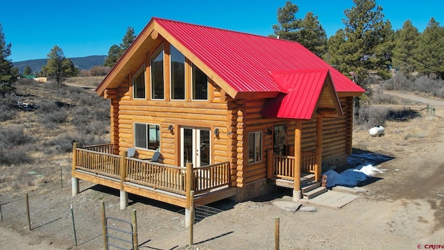 view of front of house featuring french doors, a standing seam roof, metal roof, log exterior, and a mountain view