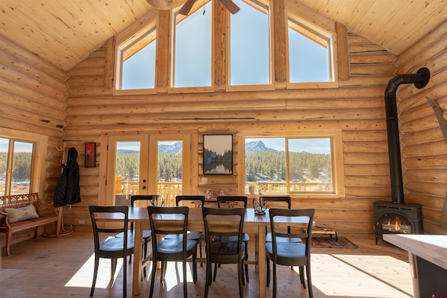 dining space featuring french doors, log walls, a wood stove, wooden ceiling, and hardwood / wood-style floors