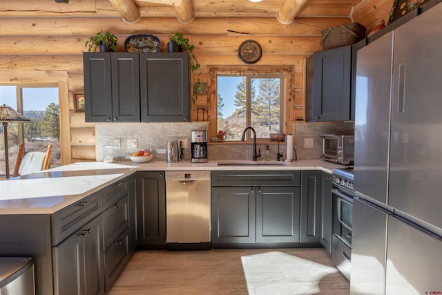 kitchen featuring a peninsula, tasteful backsplash, stainless steel appliances, and a sink