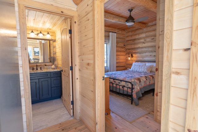 bedroom featuring wooden ceiling, a sink, light wood-type flooring, log walls, and beamed ceiling