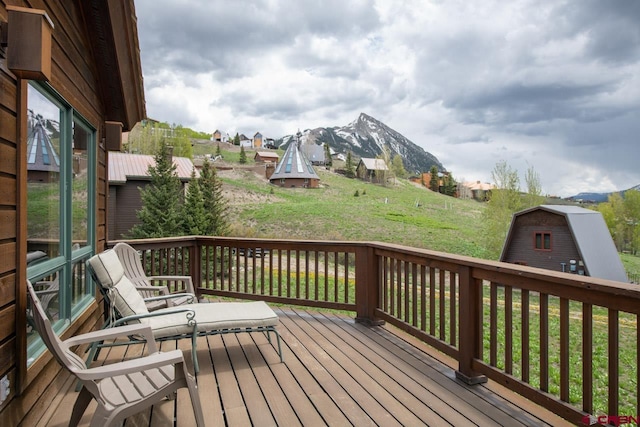 wooden terrace featuring a mountain view and a yard