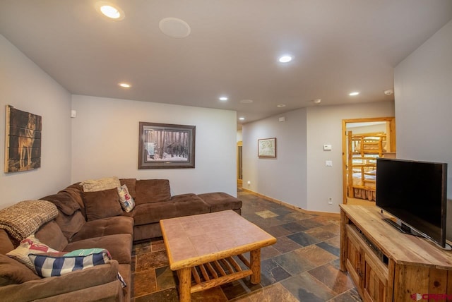 living area with baseboards, stone tile flooring, and recessed lighting