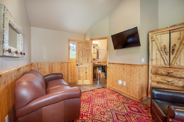 living area featuring lofted ceiling, wood walls, and wainscoting