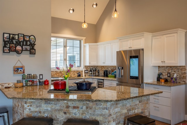 kitchen featuring decorative backsplash, wine cooler, a peninsula, light stone countertops, and stainless steel appliances