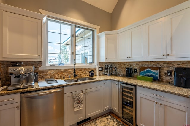 kitchen featuring backsplash, stainless steel dishwasher, white cabinets, a sink, and beverage cooler