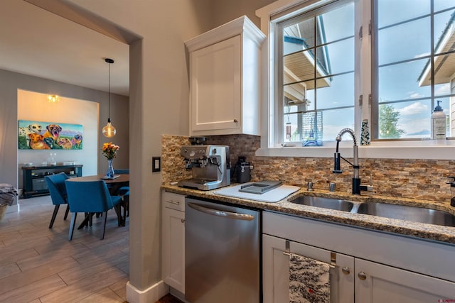 kitchen featuring white cabinets, dishwasher, backsplash, stone counters, and a sink