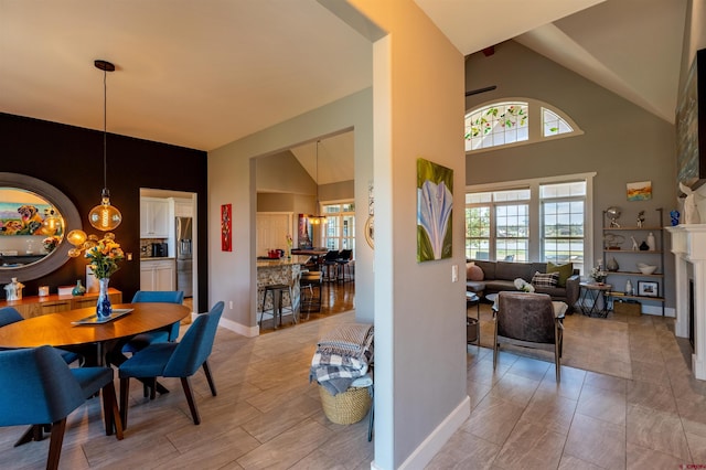 dining area featuring high vaulted ceiling, a fireplace, and baseboards