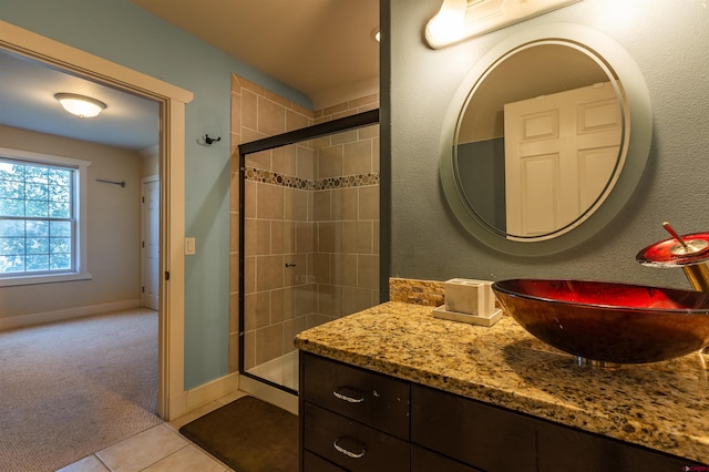 bathroom with baseboards, a shower stall, vanity, and tile patterned floors