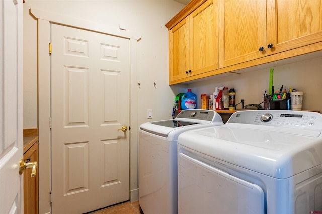 laundry room with light tile patterned floors, washer and clothes dryer, and cabinet space