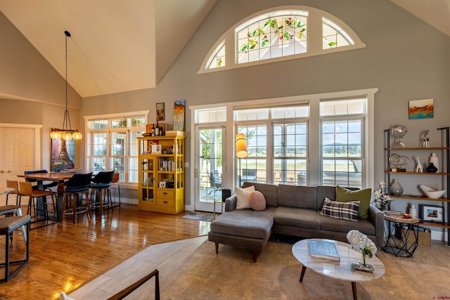 living room with a notable chandelier, high vaulted ceiling, and wood finished floors