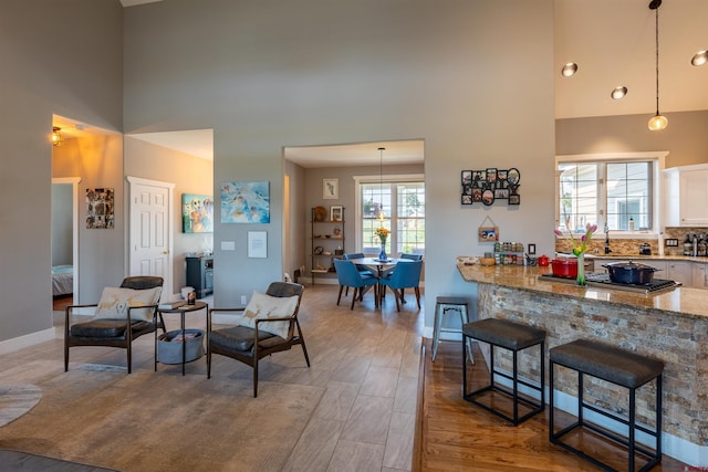 interior space with wood finished floors, white cabinets, light stone countertops, a kitchen bar, and pendant lighting