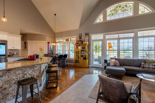 living area with high vaulted ceiling and wood finished floors