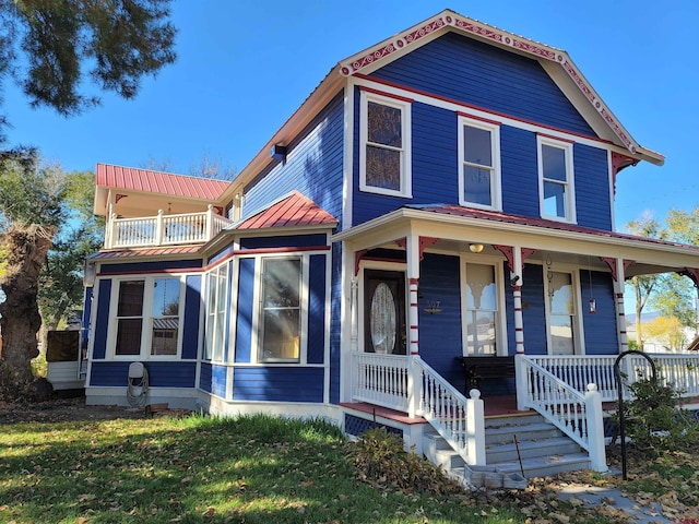 view of front of house with metal roof, a porch, a front lawn, and a balcony