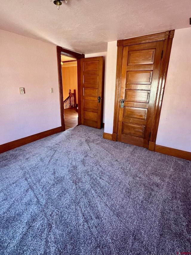 unfurnished bedroom with carpet, a textured ceiling, and baseboards