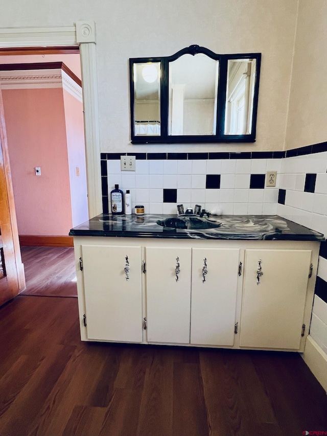 kitchen with dark wood-style flooring, dark countertops, a sink, and white cabinets