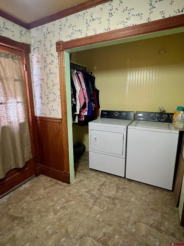 clothes washing area featuring wallpapered walls, laundry area, washer and clothes dryer, and wainscoting