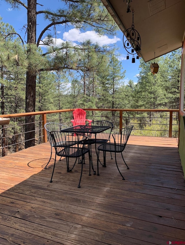 wooden terrace featuring visible vents and outdoor dining area