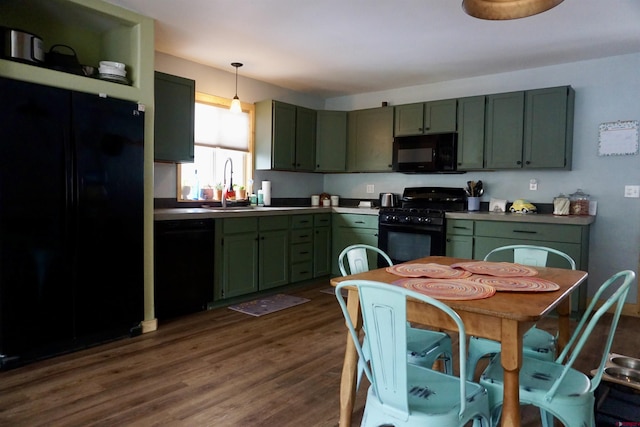 kitchen featuring dark wood-style flooring, decorative light fixtures, a sink, green cabinetry, and black appliances