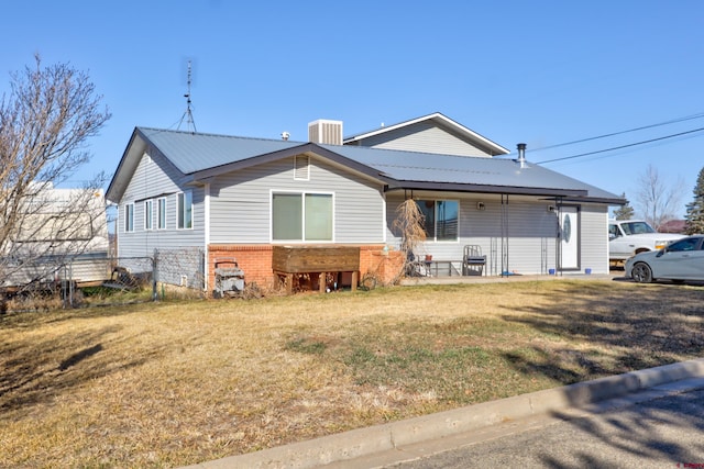 exterior space with metal roof, central AC, a front lawn, and brick siding