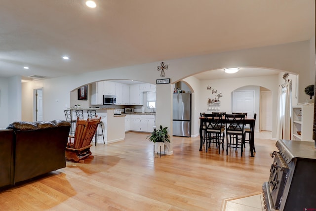 dining room with light wood-style floors, visible vents, arched walkways, and recessed lighting