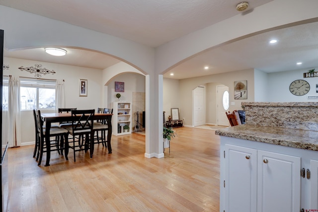 dining area featuring light wood-type flooring, baseboards, arched walkways, and recessed lighting