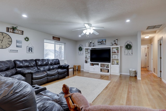 living area featuring a textured ceiling, light wood finished floors, visible vents, and recessed lighting