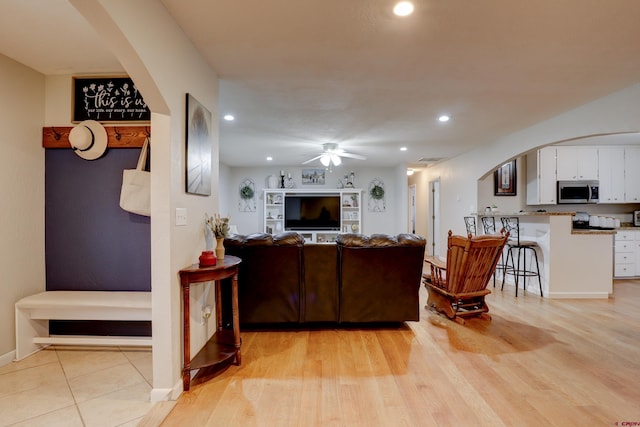 living room with arched walkways, recessed lighting, a ceiling fan, baseboards, and light wood-type flooring