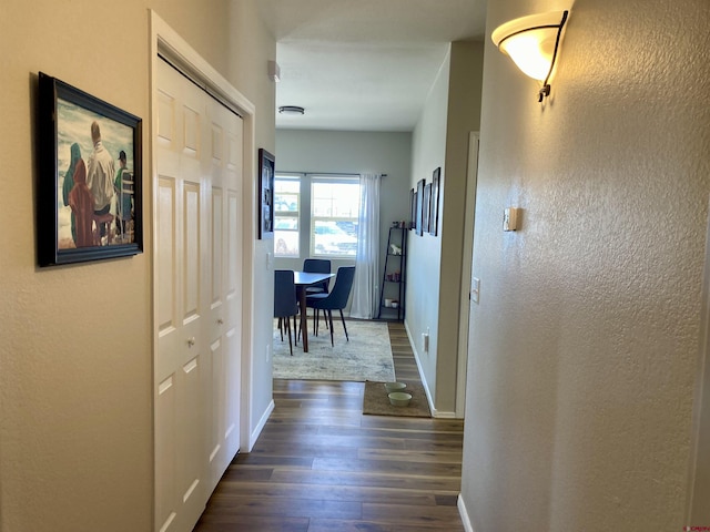 hallway with dark wood-style flooring and baseboards