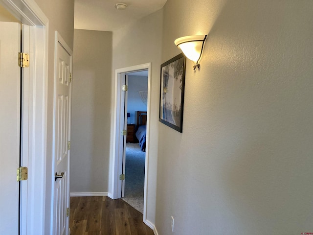 hallway featuring dark wood-style flooring and baseboards