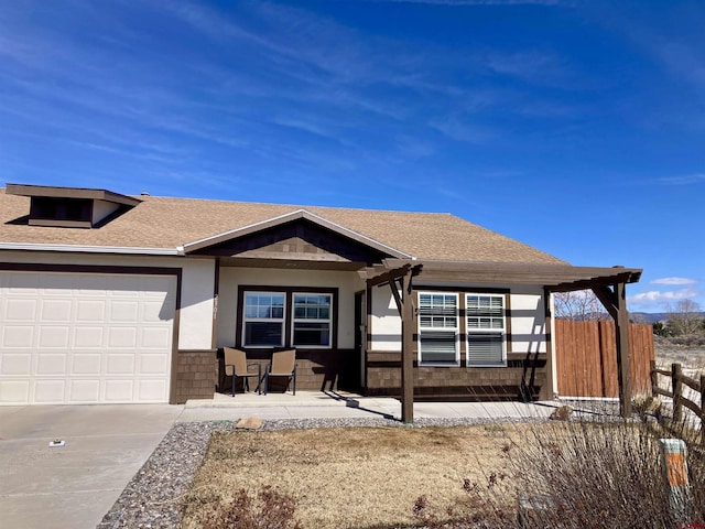 view of front facade featuring an attached garage, a shingled roof, fence, and stucco siding