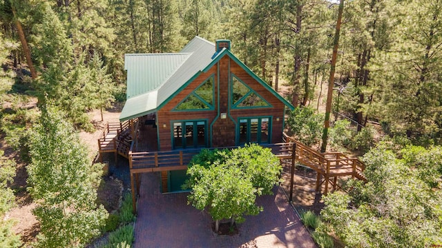 view of front of house featuring stairs, metal roof, a wooded view, and french doors