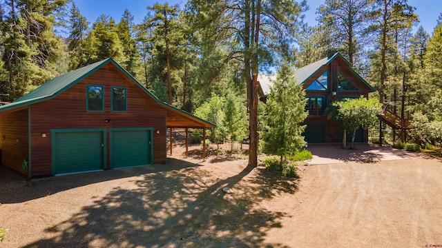 exterior space with dirt driveway, metal roof, an outbuilding, and a detached garage