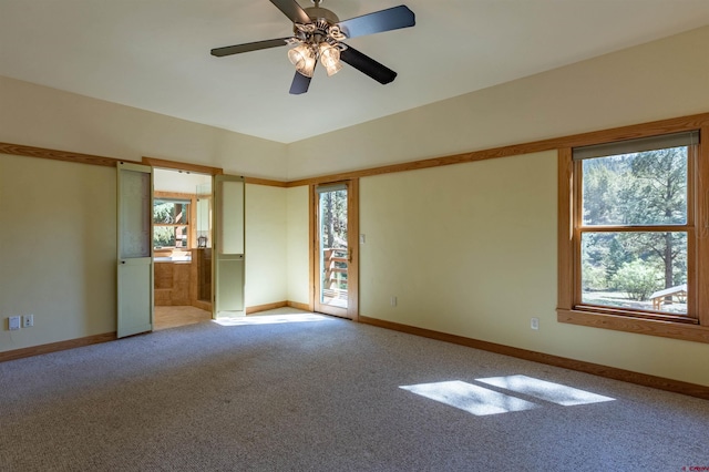 carpeted spare room featuring ceiling fan and baseboards