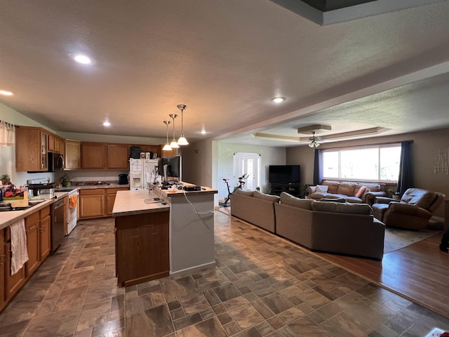 kitchen featuring open floor plan, appliances with stainless steel finishes, a center island, and a raised ceiling