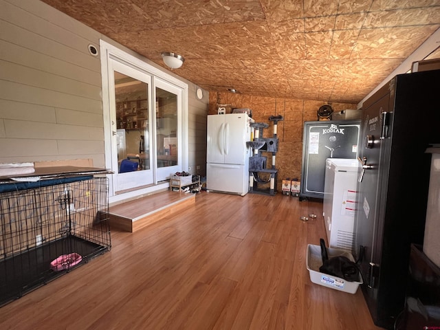 interior space with wooden walls, wood finished floors, and freestanding refrigerator