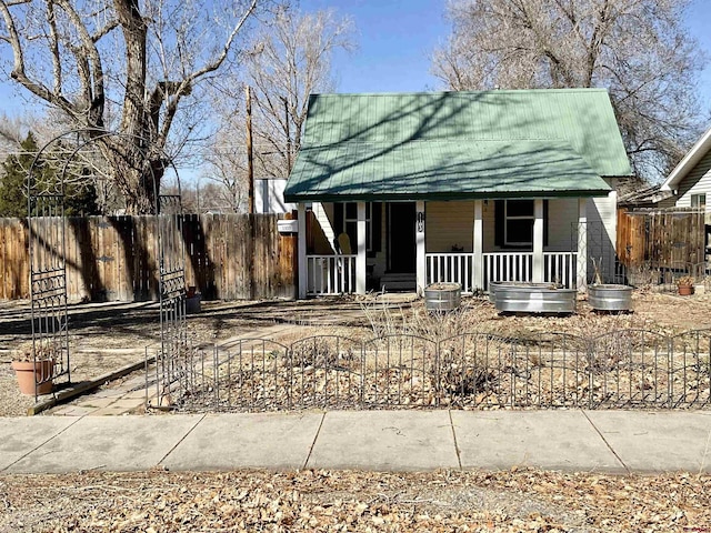 view of front of house with fence, covered porch, and metal roof