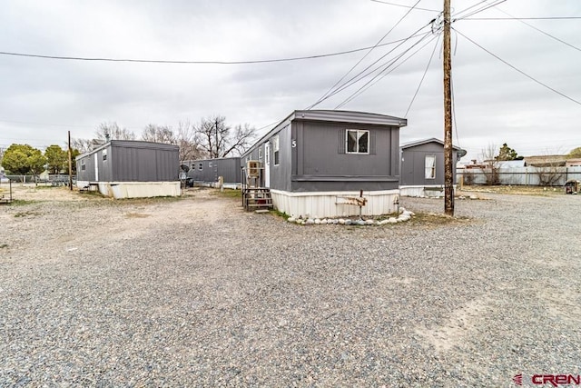 view of front of home with an outdoor structure, driveway, and fence