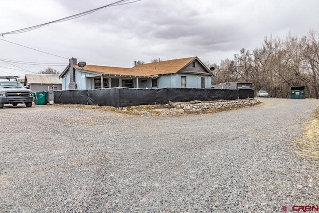 view of front facade featuring gravel driveway and fence