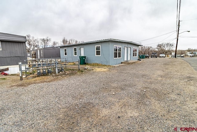 rear view of house featuring driveway and fence