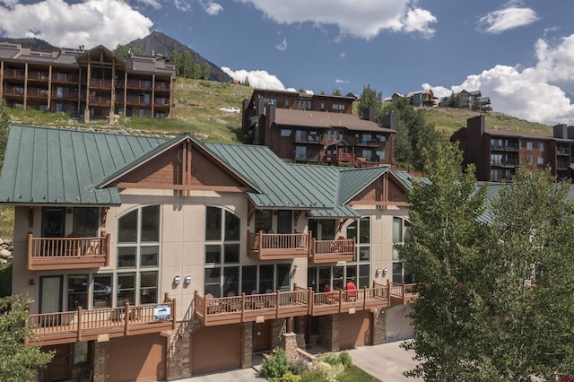 exterior space with driveway, a standing seam roof, a mountain view, an attached garage, and metal roof