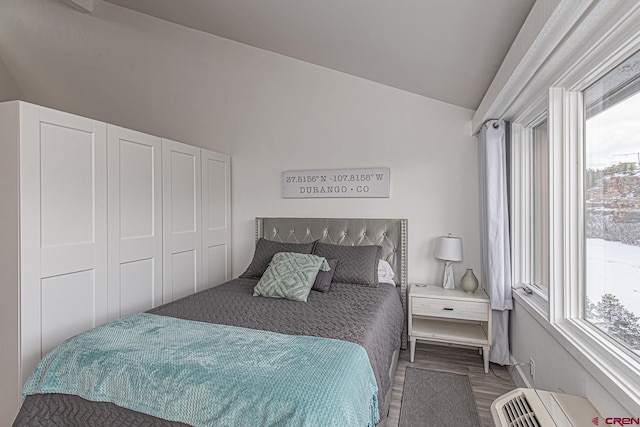 bedroom featuring wood finished floors, a wall mounted AC, and vaulted ceiling