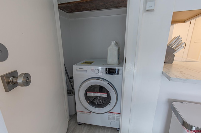 clothes washing area with light wood-type flooring, washer / dryer, and laundry area