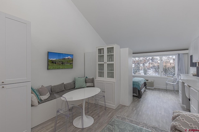 living room featuring high vaulted ceiling, light wood-style floors, and a wall unit AC