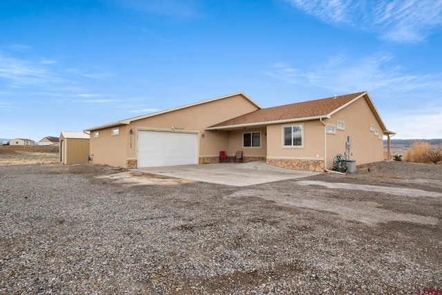 view of front facade with a garage, stone siding, driveway, and stucco siding