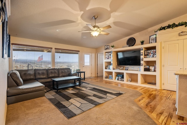 living room featuring a ceiling fan, vaulted ceiling, and wood finished floors