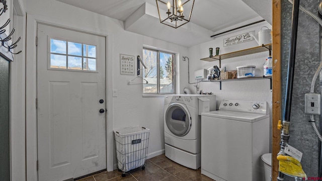 clothes washing area with dark tile patterned flooring, a notable chandelier, and independent washer and dryer