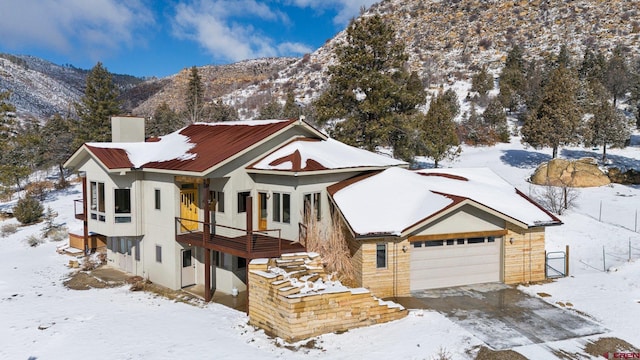 view of front of house with a garage, a mountain view, a chimney, and stucco siding