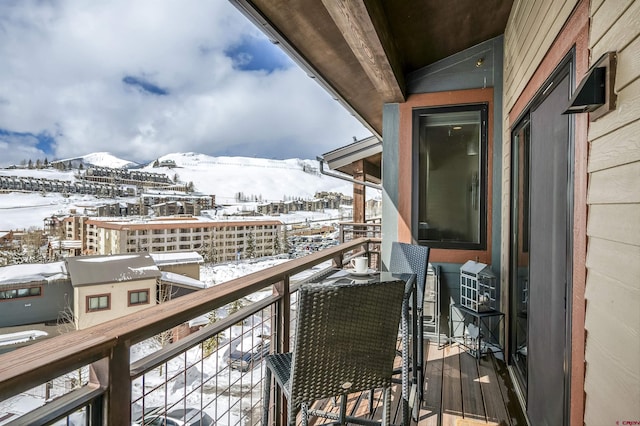 snow covered back of property featuring a mountain view